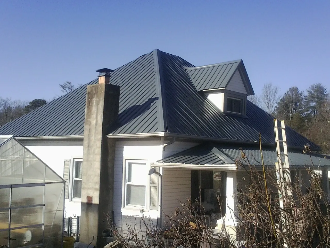 Dark blue standing seam metal roof on a white farmhouse with dormer — Slate & Tile Roof Repair by Roofing Brothers in Duquesne