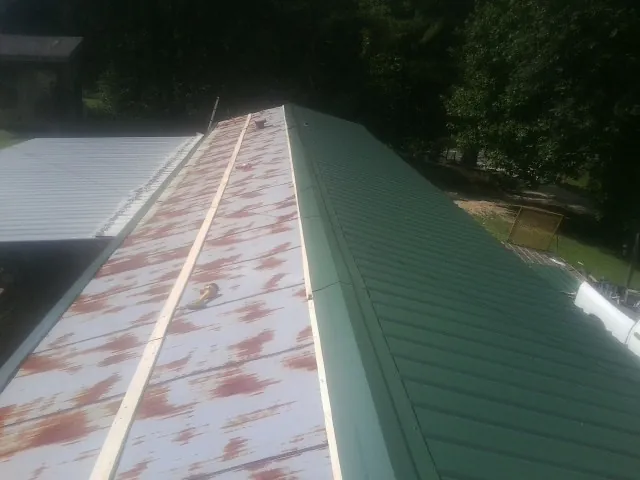 Old rusted panels beside newly installed green metal roofing — Wind Damage Roof Repair by Roofing Brothers in Duquesne
