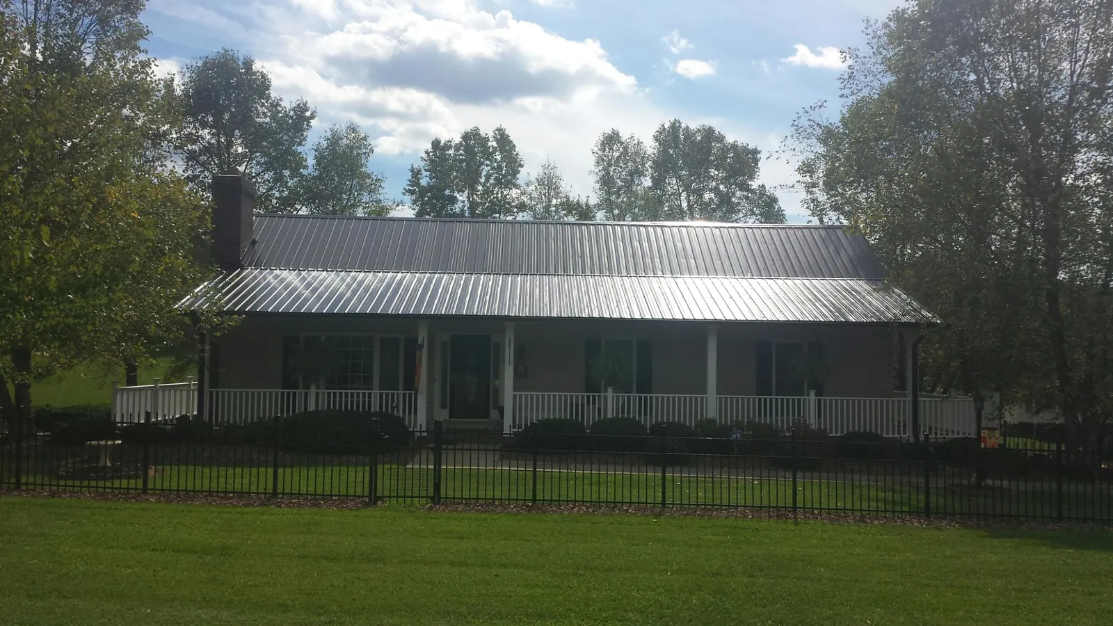 Gray metal roof on a brick ranch with a full width front porch — Gutter Guard Installation work by our crew in Duquesne