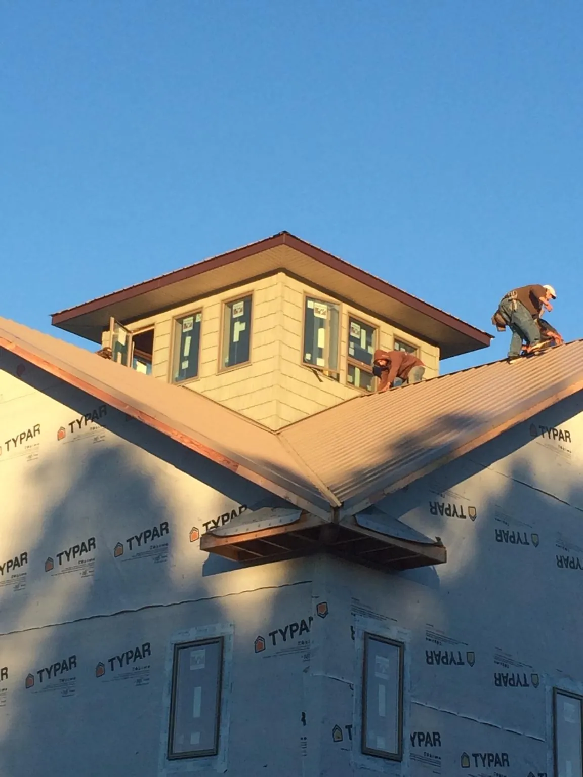 Roofers working around a rooftop cupola on a new metal roof at sunset — Roof Waterproofing in Duquesne by Roofing Brothers